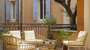 A balcony with wicker furniture, including two chairs and a small table, surrounded by potted plants. - Grand Hôtel d’Orange, BW Signature Collection (Orange)