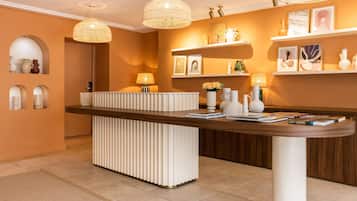 A reception area with a wooden reception desk, white decorative elements, and hanging wicker lamps.