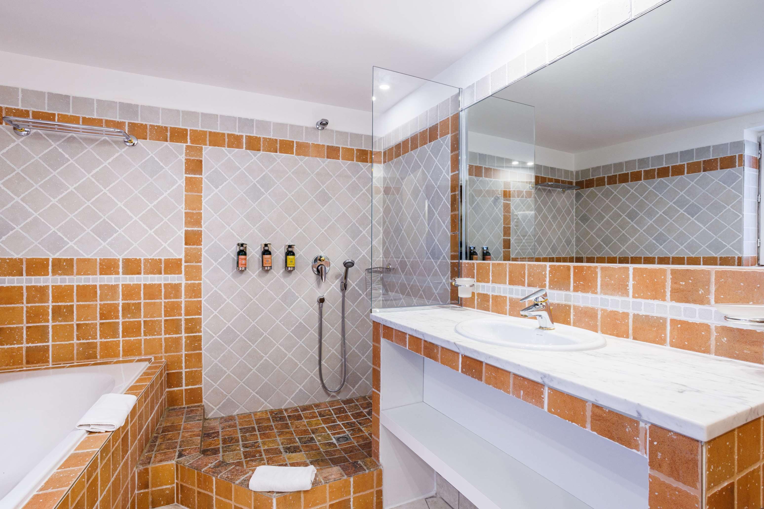 A modern bathroom with a bathtub, shower, and sink, featuring a tiled backsplash and a large mirror.