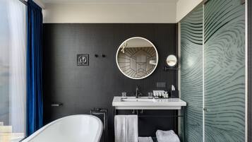 A modern bathroom with a freestanding bathtub, a round mirror, and a glass shower enclosure.