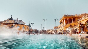 Ein großer Pool im Freien mit aufsteigendem Dampf, umgeben von klassischer Architektur.