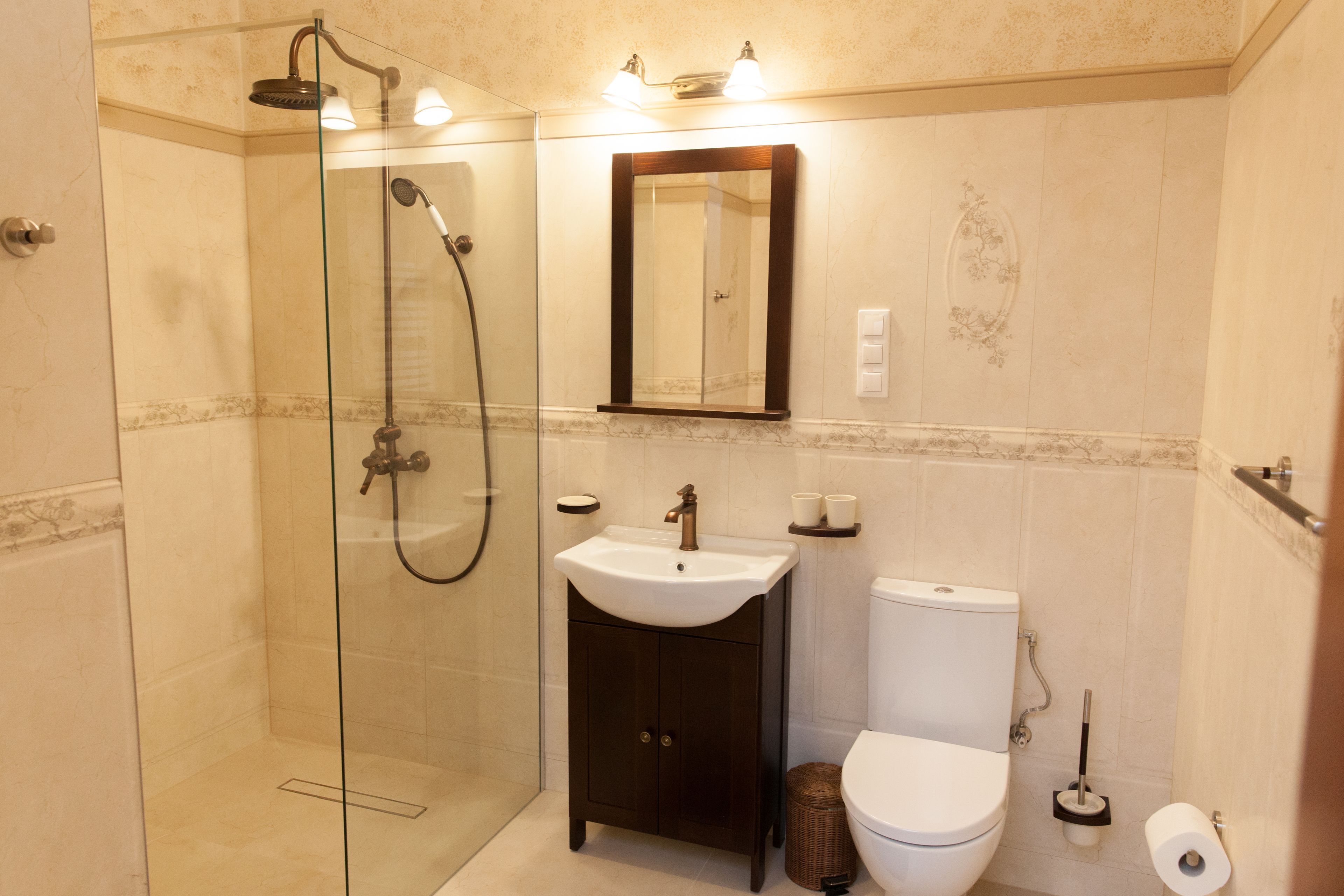 A modern bathroom with a glass-enclosed shower, a pedestal sink, a toilet, and a mirror above the sink.