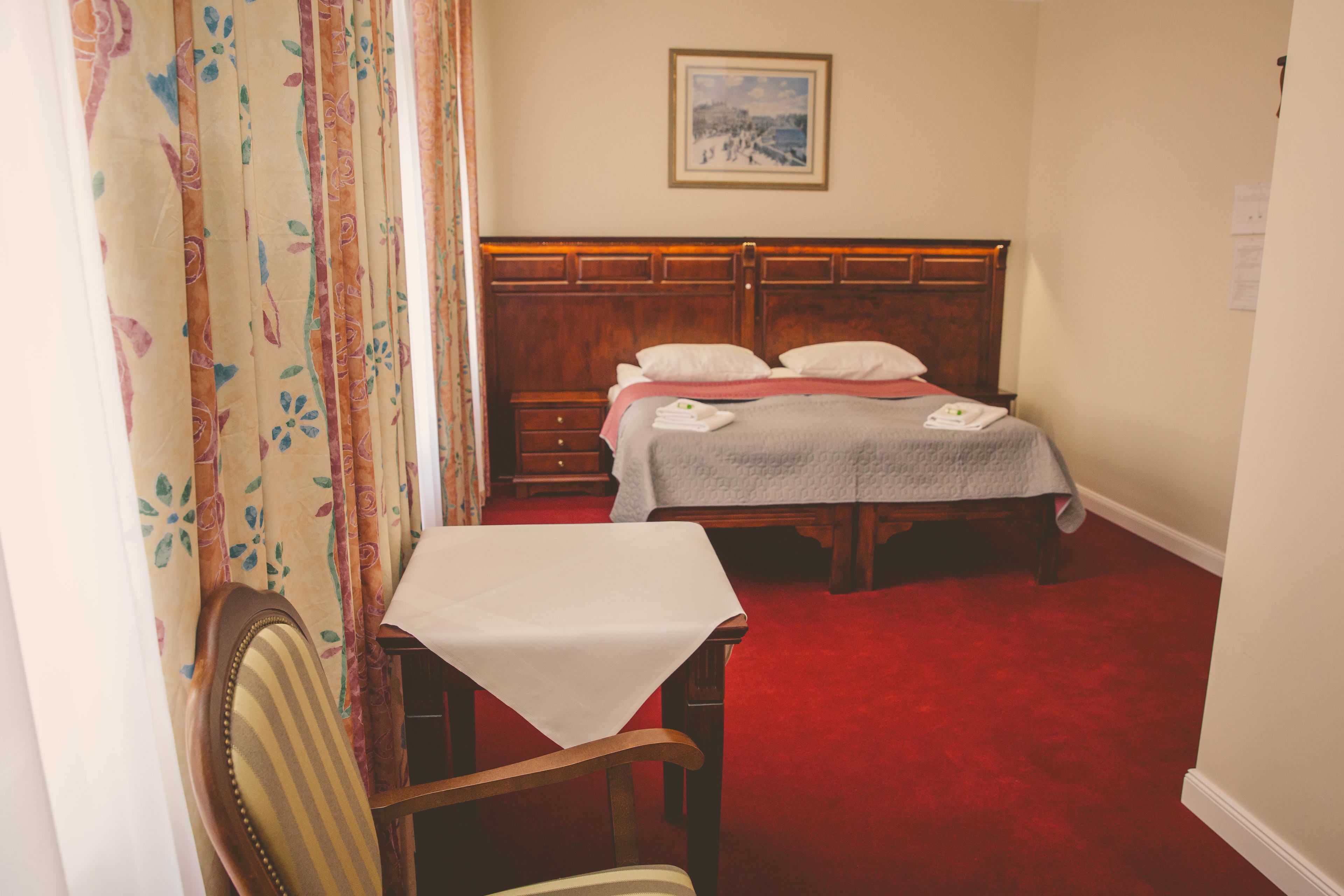 A bedroom with a wooden bed, a bedside table, and a chair.