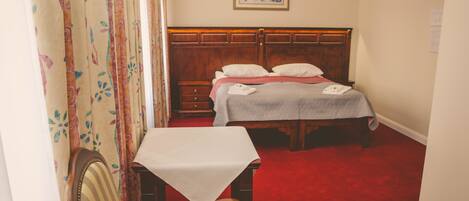 A bedroom with a wooden bed, a bedside table, and a chair.