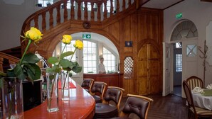 A wooden interior with a curved table, chairs, and vases with flowers. - Hotel Willa Starosty (Miedzyrzecz)