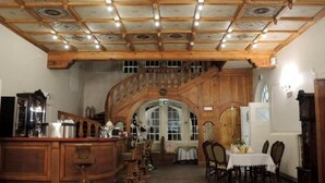 A spacious room with a wooden staircase, a dining area, and a bar. - Hotel Willa Starosty (Miedzyrzecz)
