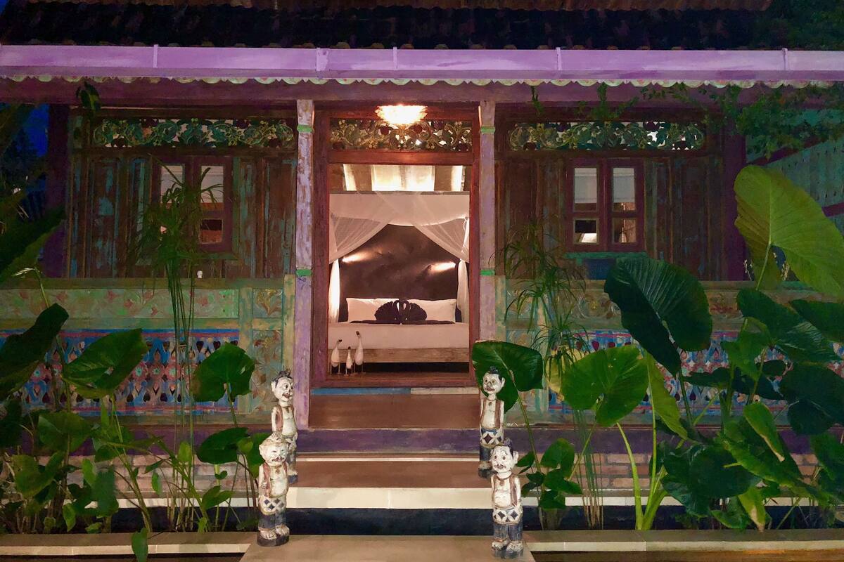 A traditional room with a bed, a window, and a decorative entrance with two statues.