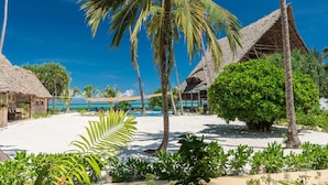 A beach resort with thatched-roof huts, palm trees, and a clear blue sky. - Zanzibar Magic Boutique Hotel (Matemwe)
