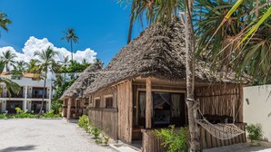 A beachside bungalow with a thatched roof, wooden walls, and a hammock. - Zanzibar Magic Boutique Hotel (Matemwe)
