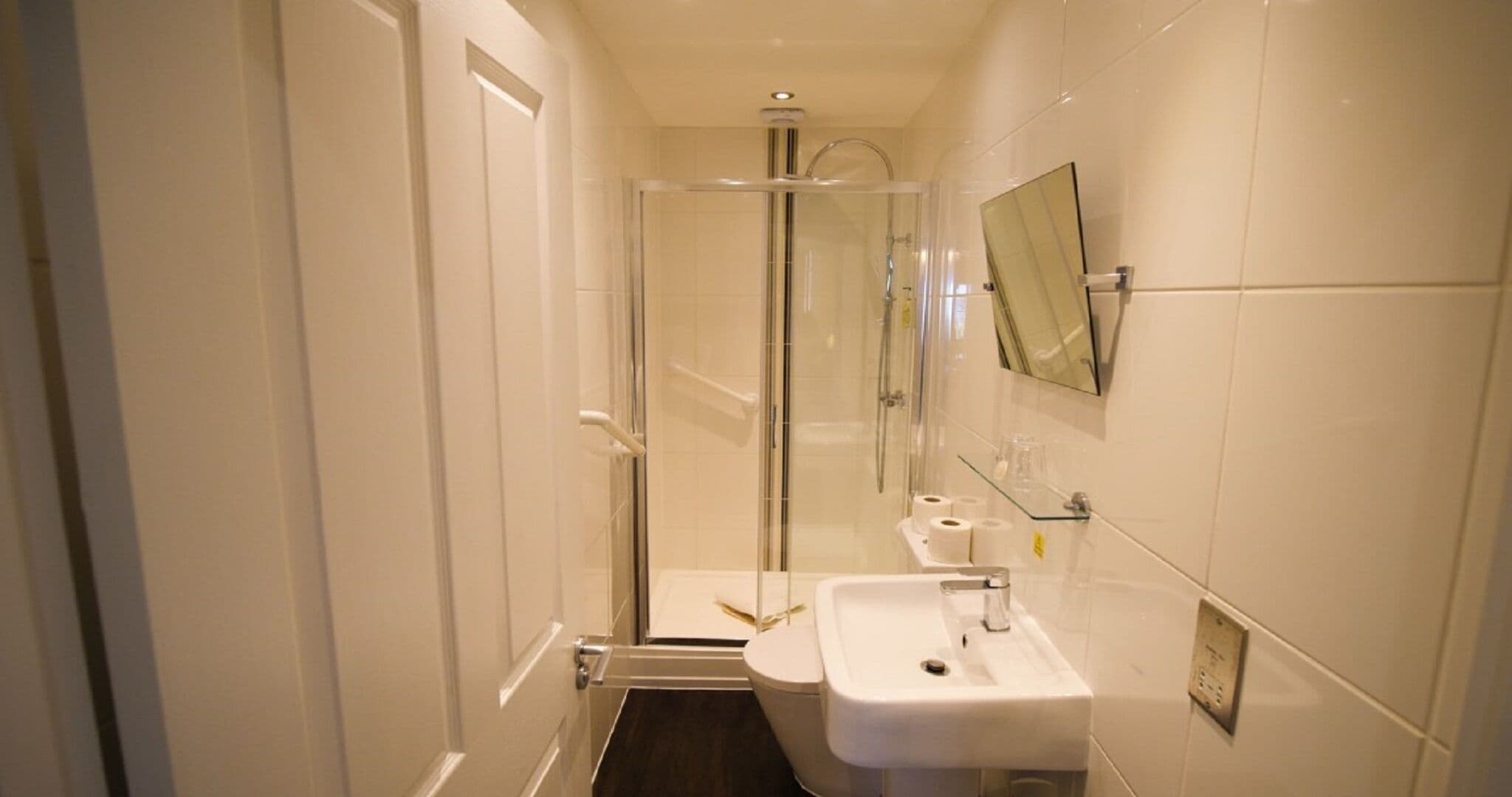 Un baño moderno con cabina de ducha de vidrio, un lavabo blanco y un espejo en la pared.