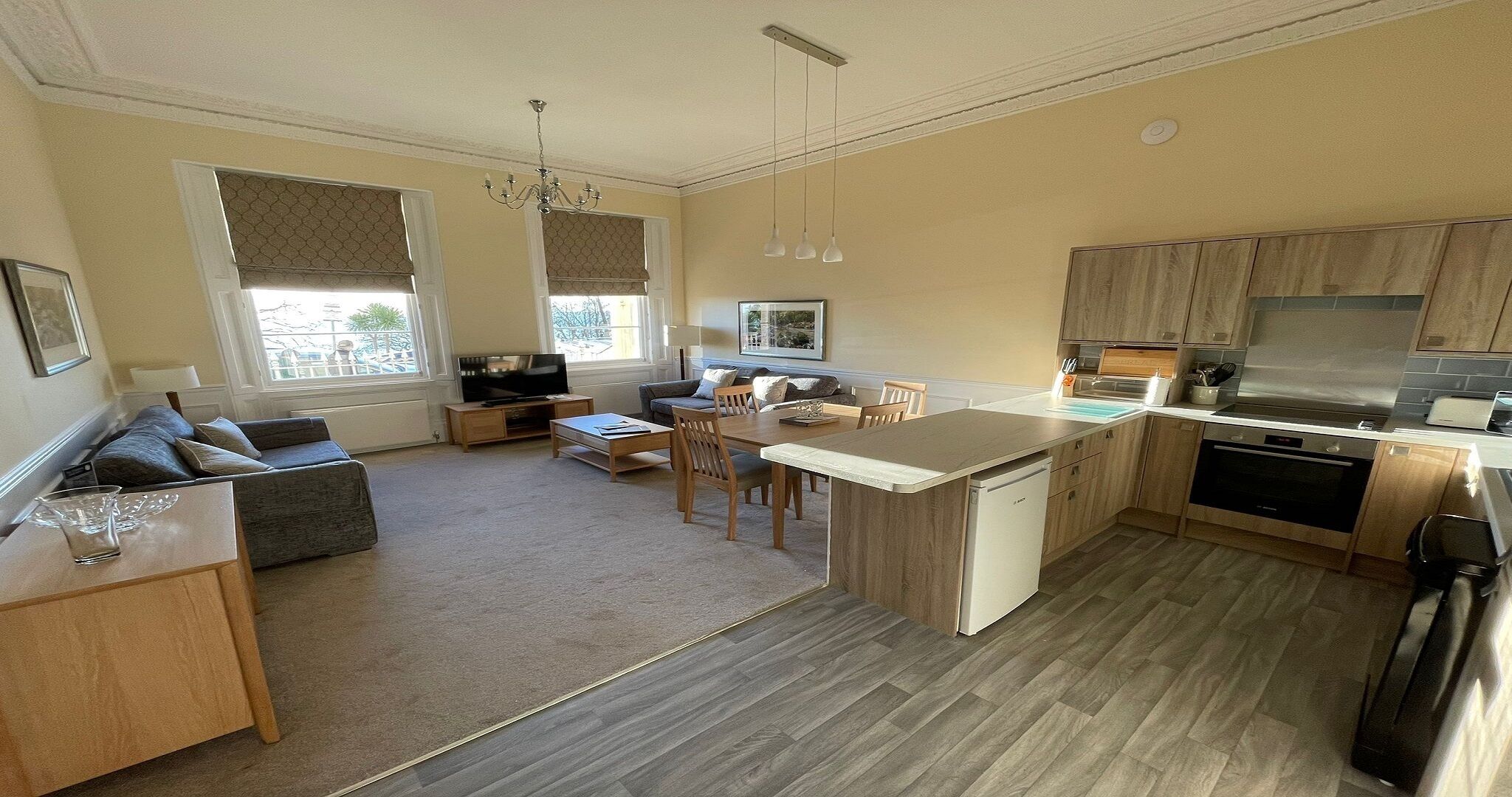 Una cocina moderna con armarios de madera, una isla central y un área de comedor con sofá y sillas.