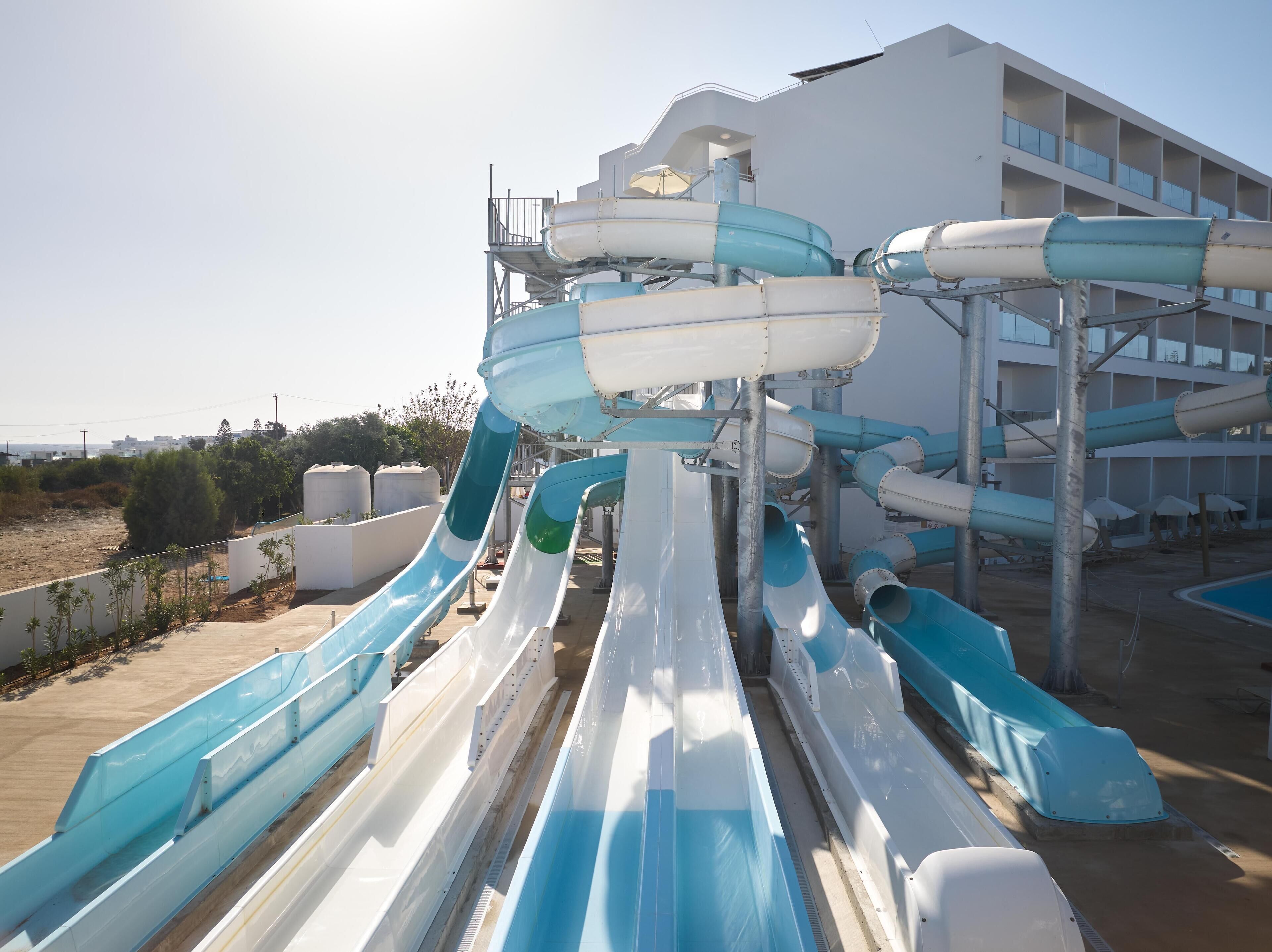 A water park with multiple water slides and a building in the background.