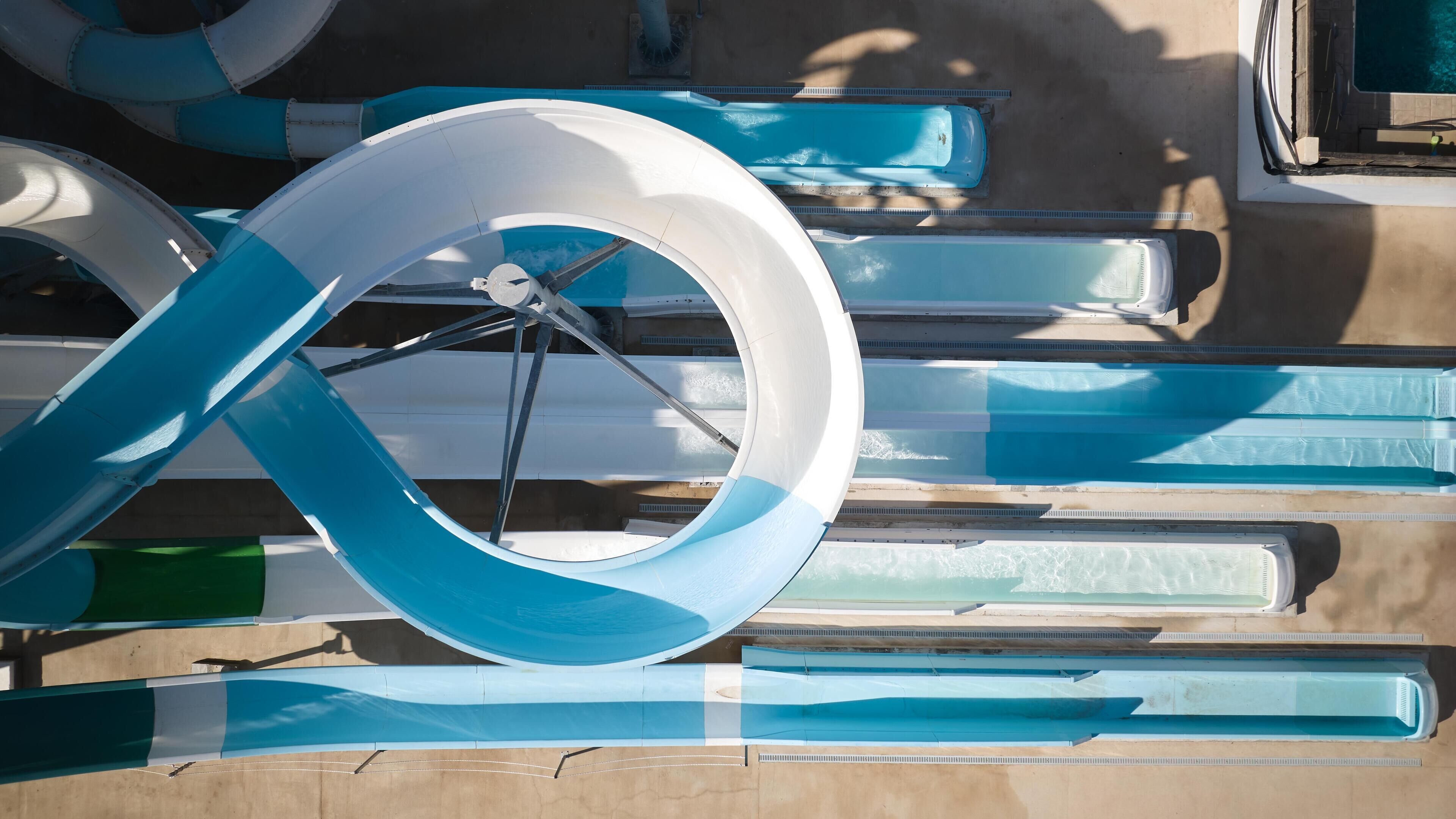 A series of blue and white water slides with a circular structure in the center.