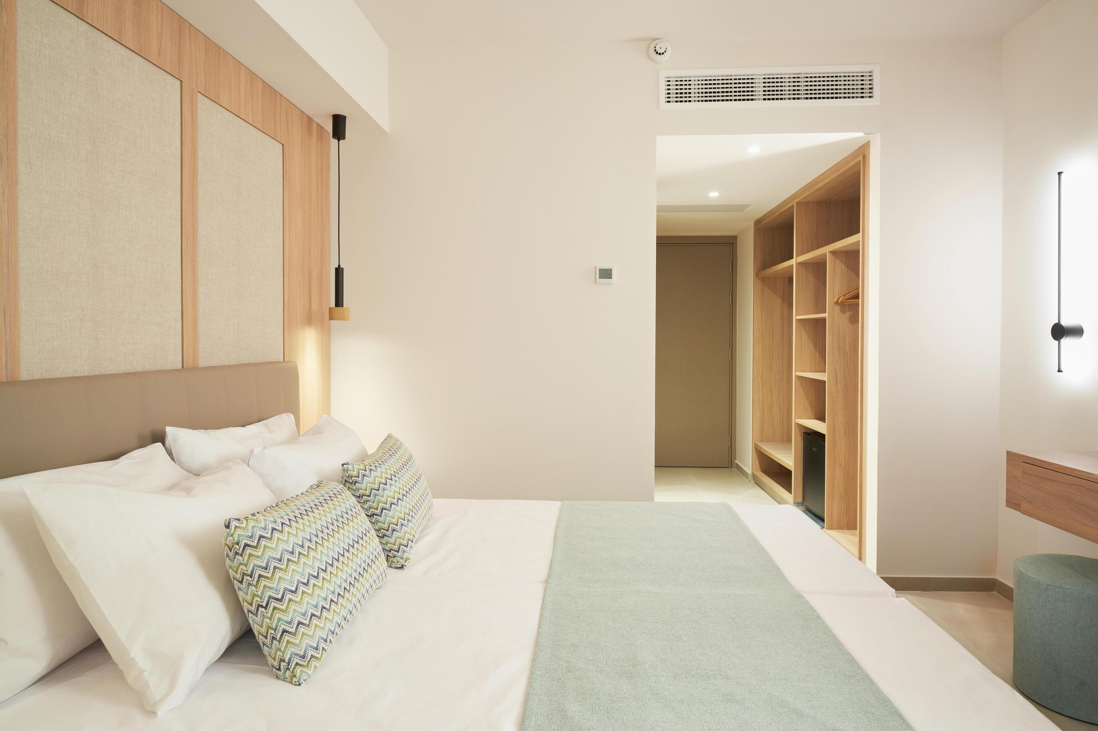 Een slaapkamer met een groot bed, een kledingkast en een nachtkastje.