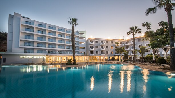 A hotel with a swimming pool, multiple balconies, and palm trees. - Narcissos Waterpark Resort (Paralimni)