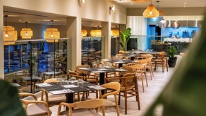 A restaurant with round tables, wicker chairs, and hanging wicker lamps. - Narcissos Waterpark Resort (Paralimni)