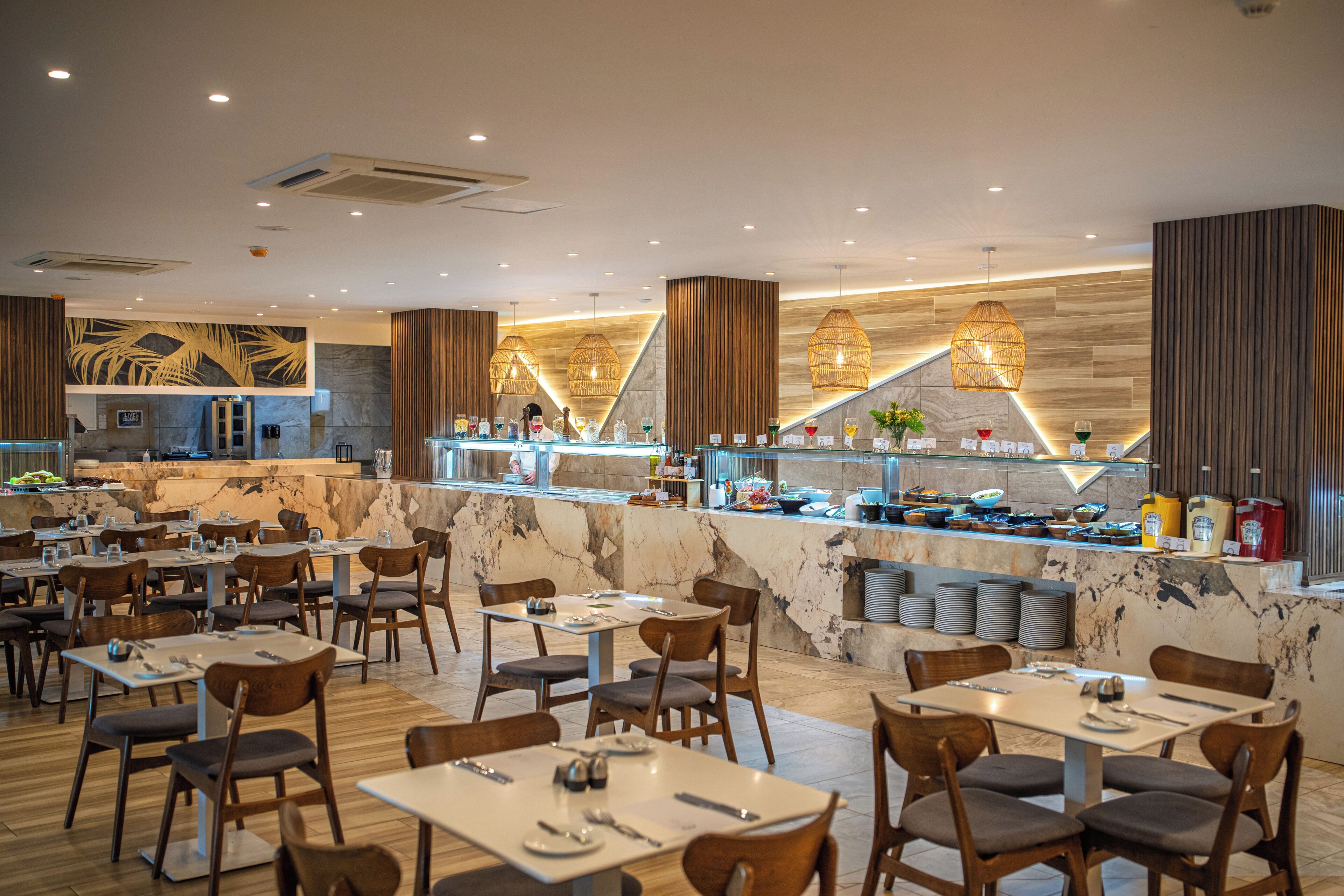 Un restaurant aux murs de marbre, aux chaises en bois et doté d’un comptoir où sont exposés divers plats.