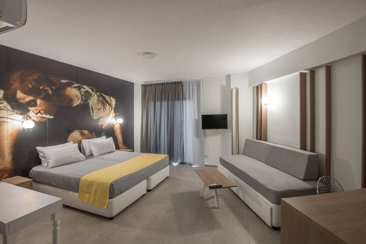 Ein modernes Hotelzimmer mit Bett, einer Sitzecke, einem Fernseher und einem großen Wandbild.