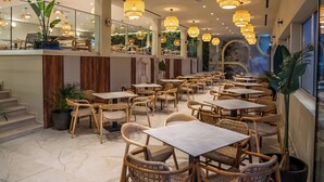 A restaurant with multiple tables and chairs, a staircase, and hanging lights. - Narcissos Waterpark Resort (Paralimni)