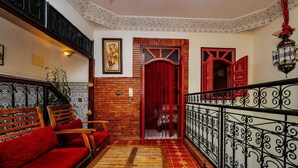 Um interior acolhedor com um banco de madeira, sofá vermelho e uma porta vermelha.
