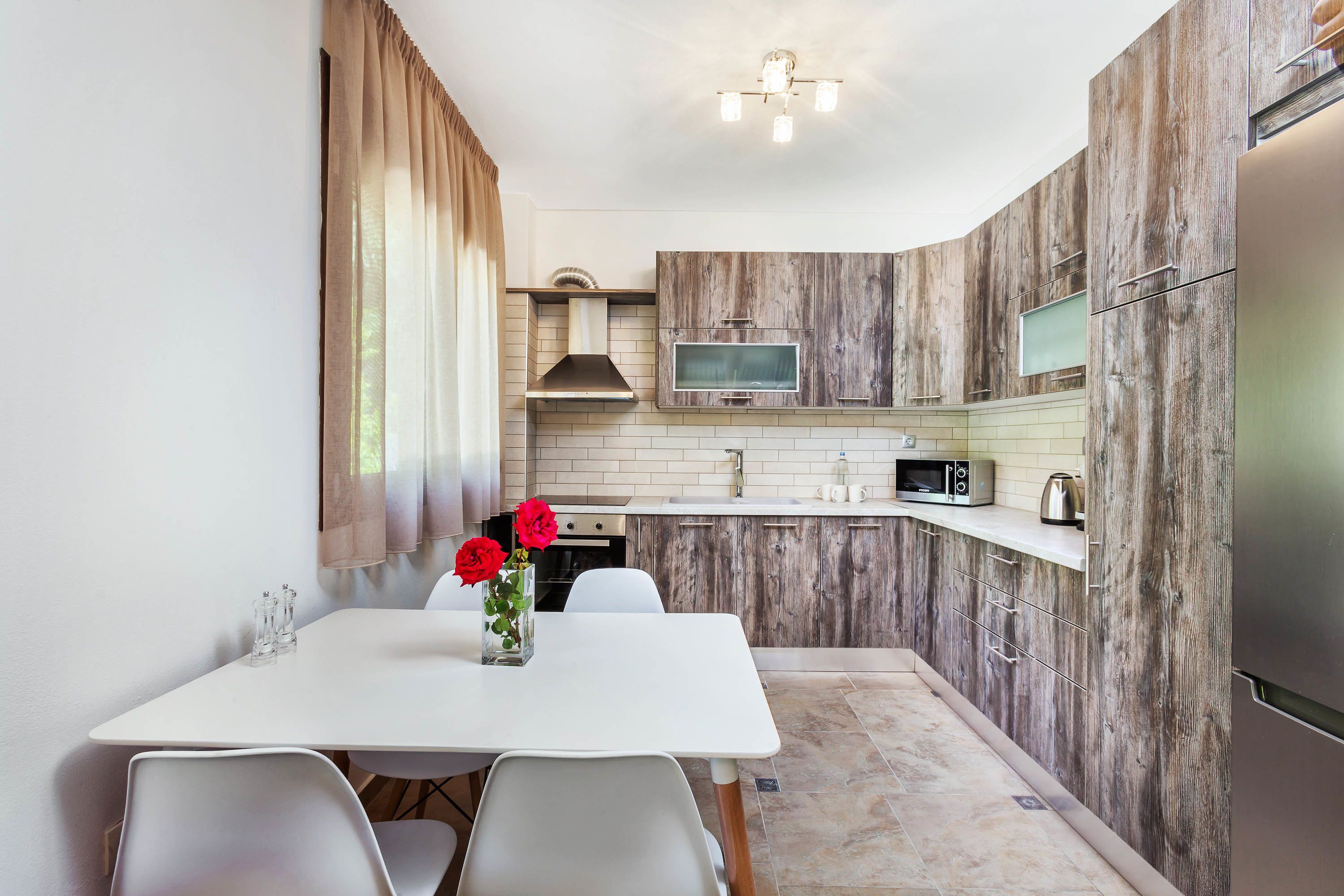 Cocina compacta con comedor, armarios de madera, microondas y refrigerador.