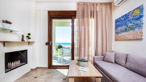 Ein Wohnzimmer mit einer Couch, einem Couchtisch, einem Kamin und Blick auf den Strand durch eine Glastür.