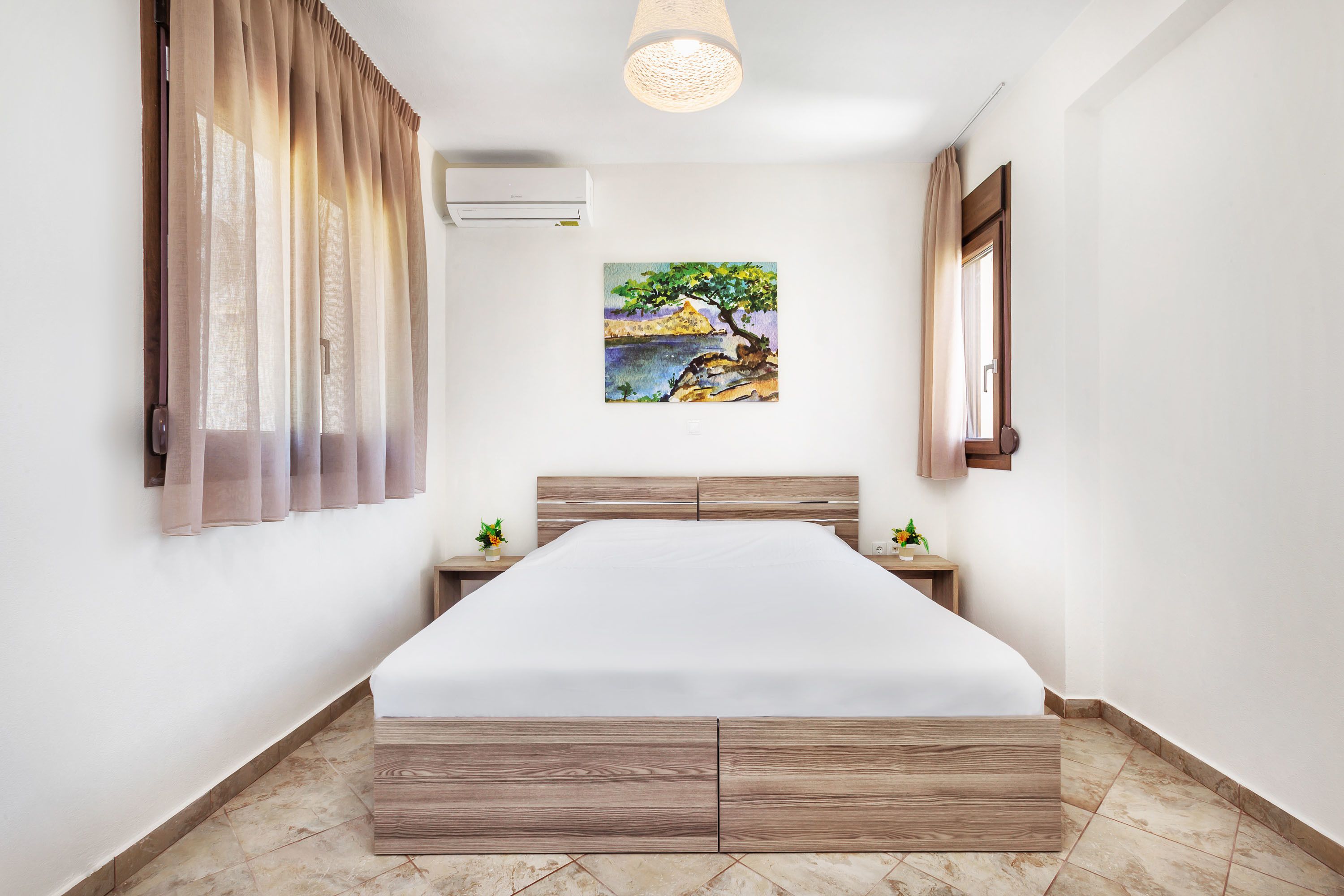Une chambre à coucher avec un lit en bois, un tableau représentant un paysage, une table de chevet et une fenêtre avec des rideaux.
