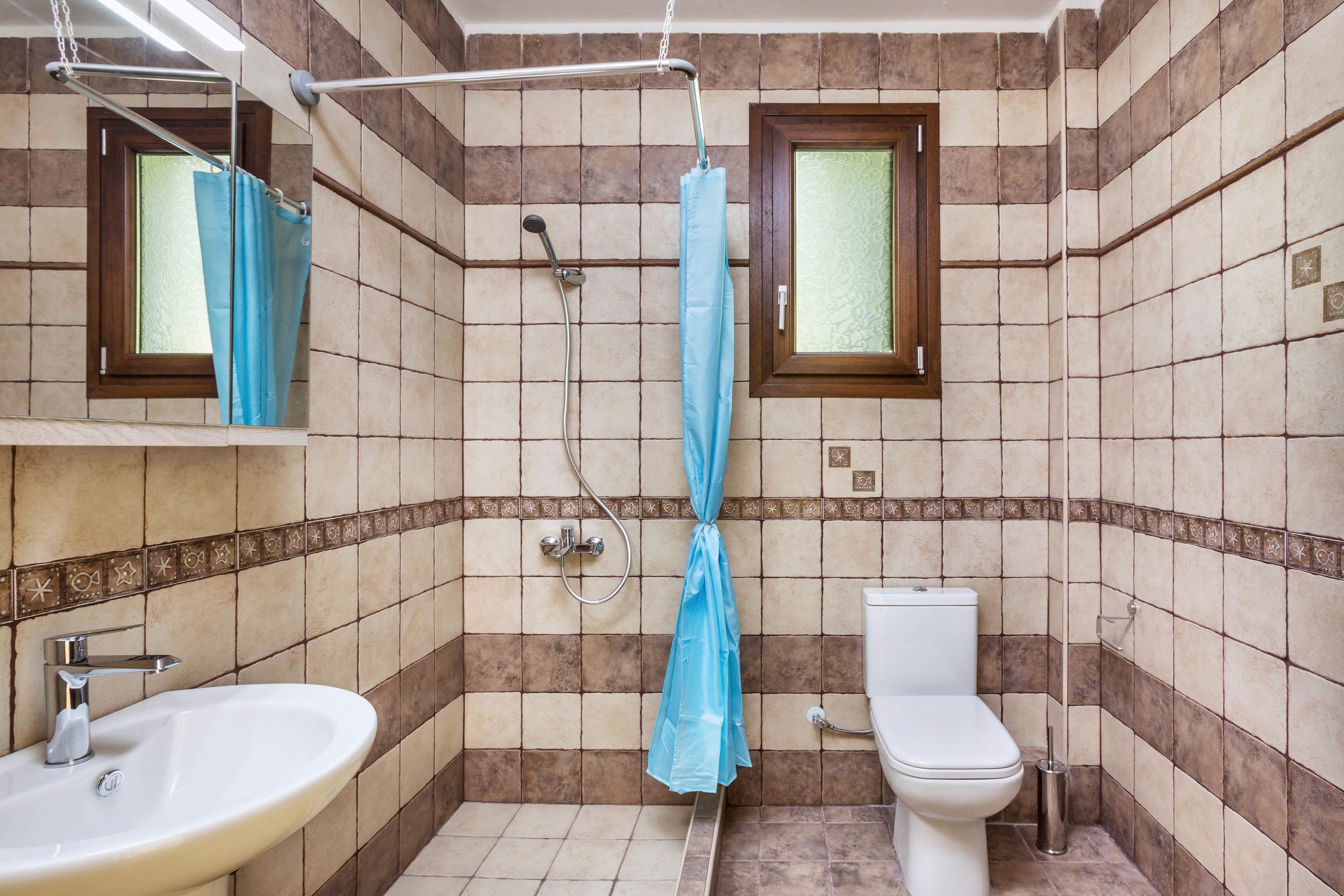 A bathroom with a sink, toilet, shower, and a window.