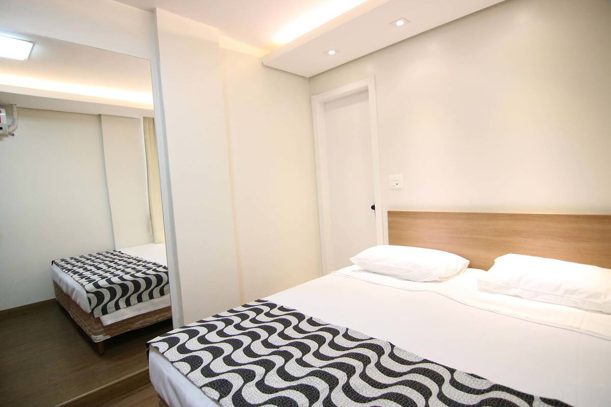 Une chambre d’hôtel avec un grand lit, un lit plus petit et une armoire.