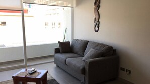 Ett vardagsrum med en grå soffa, ett litet träbord och en dekorativ väggdekoration.