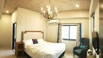 A bedroom with a bed, a chair, a TV, and a window with curtains.