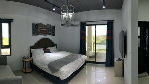 Un dormitorio moderno con una cama grande, una mesita de noche, una silla, una ventana y un balcón con cortinas.