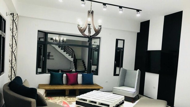 Una sala de estar moderna con sofá, reposapiés y una mesa de centro.