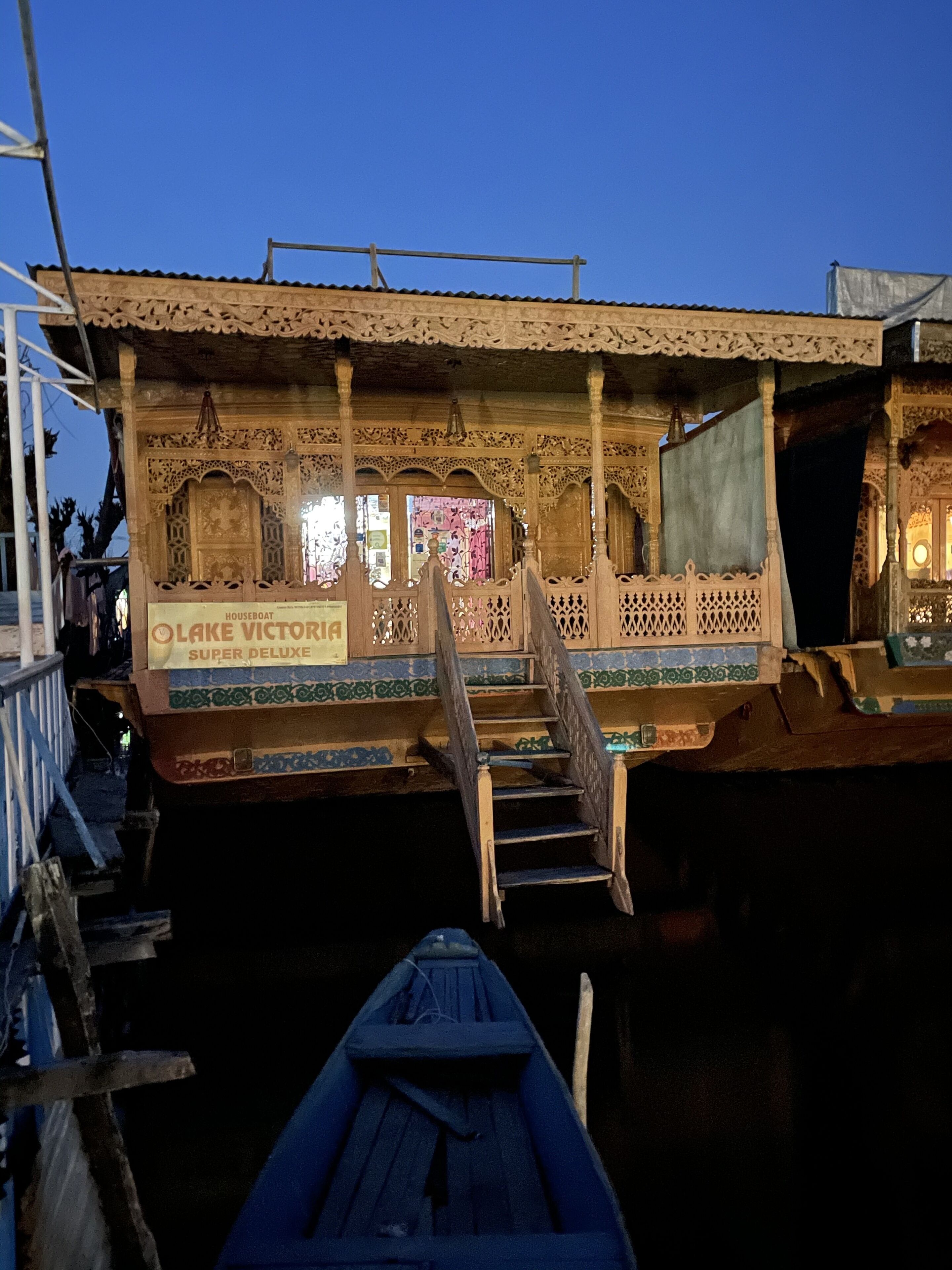 A houseboat with intricate wooden carvings and a sign that reads "Houseboat OLAKE VICTORIA SUPER DELUXE."