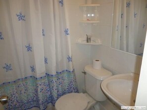 A bathroom with a toilet, a sink, and a shower curtain with a floral pattern.