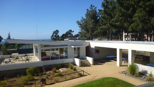 A modern building with a patio area, outdoor seating, and a view of the ocean. - Depto Algarrobo Condominio Regata 1032 (Algarrobo)