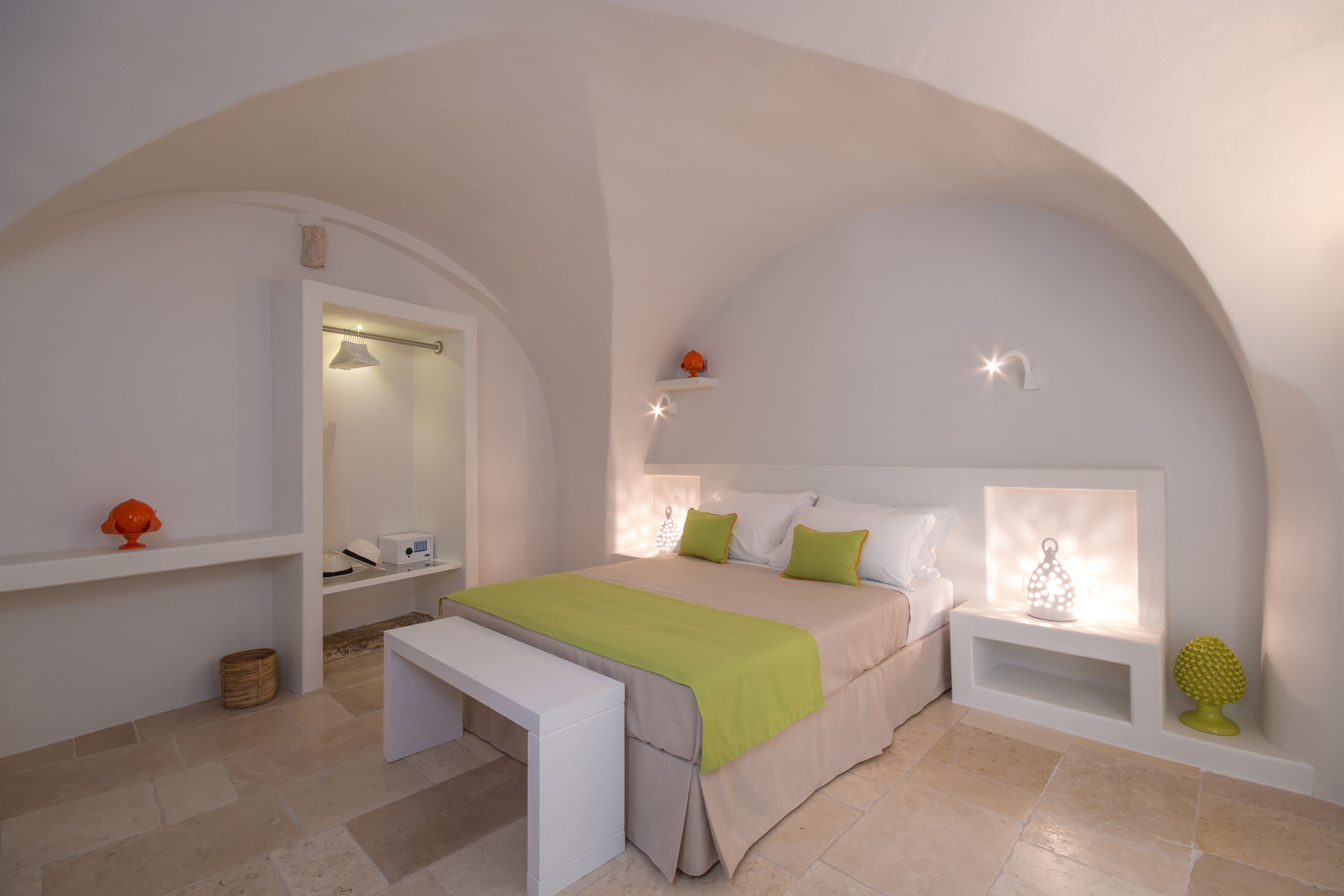 A bedroom with a bed, bedside tables, a bench, and a mirror.