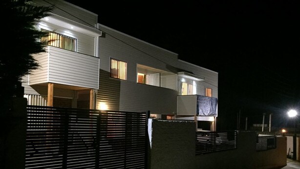 A modern two-story house with a balcony, a gated entrance, and a well-lit exterior at night. - Cabaña en Algarrobo 1 El Canelo (Algarrobo)