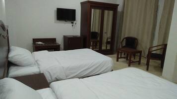Habitación de hotel con dos camas, televisión, armario, escritorio y una silla.