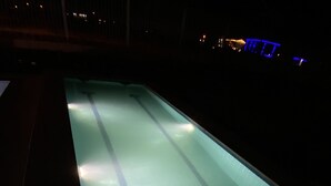 Piscina à noite com faixas de natação visíveis e um ralo no centro.