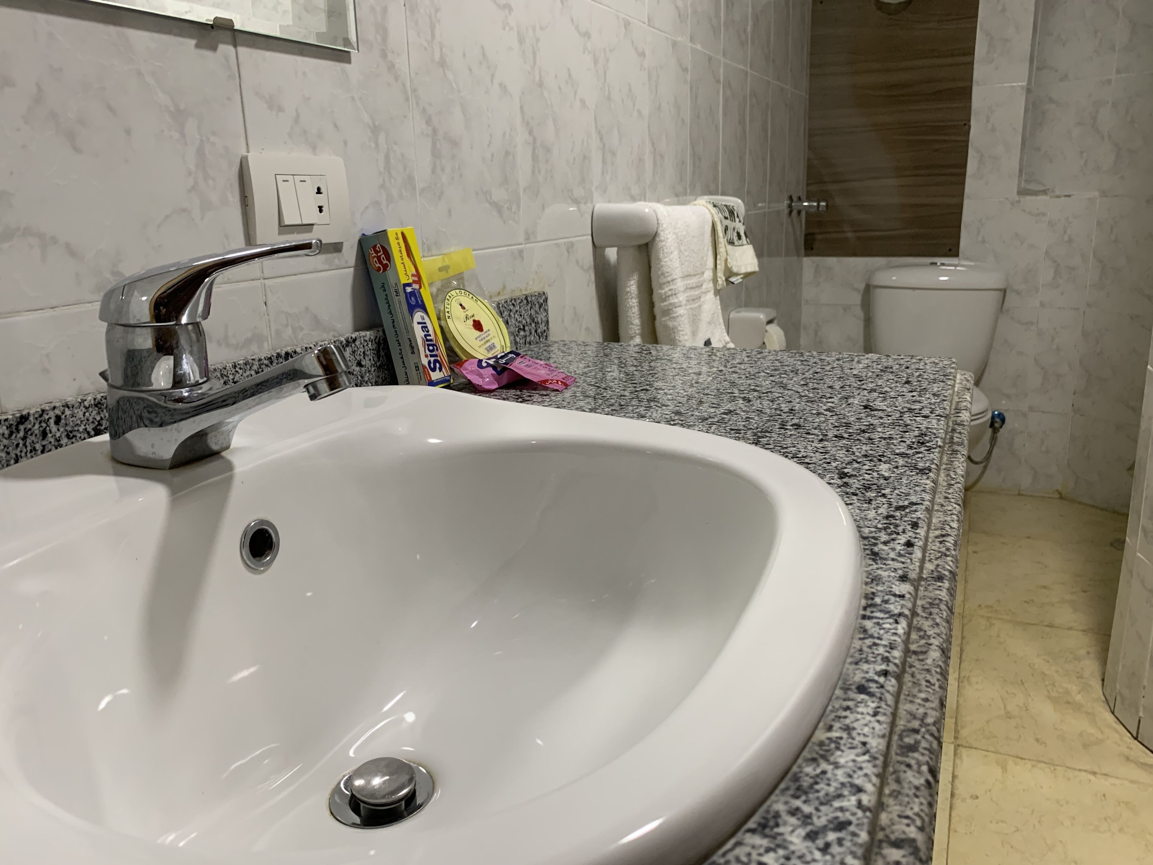 A bathroom with a white sink, granite countertop, and a toilet.
