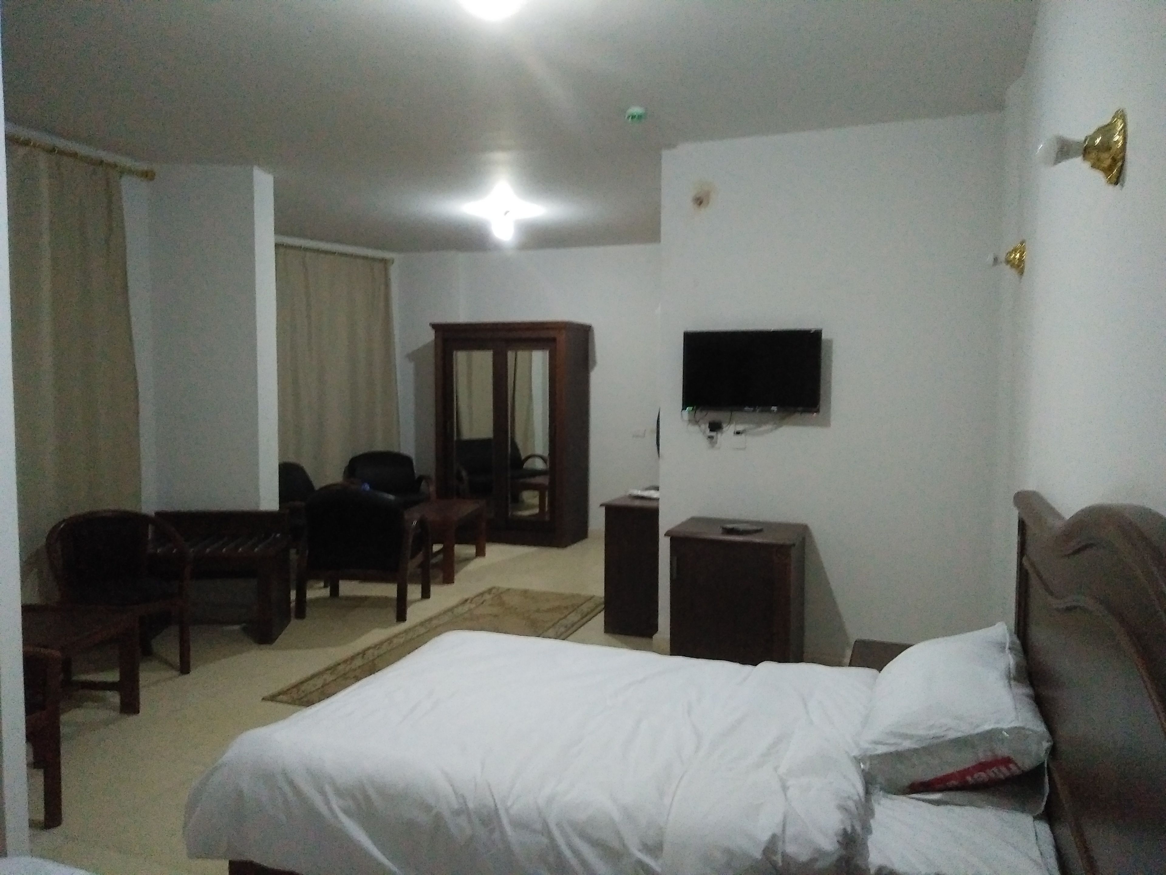 Habitación de hotel con cama, escritorio, silla, televisor y armario.