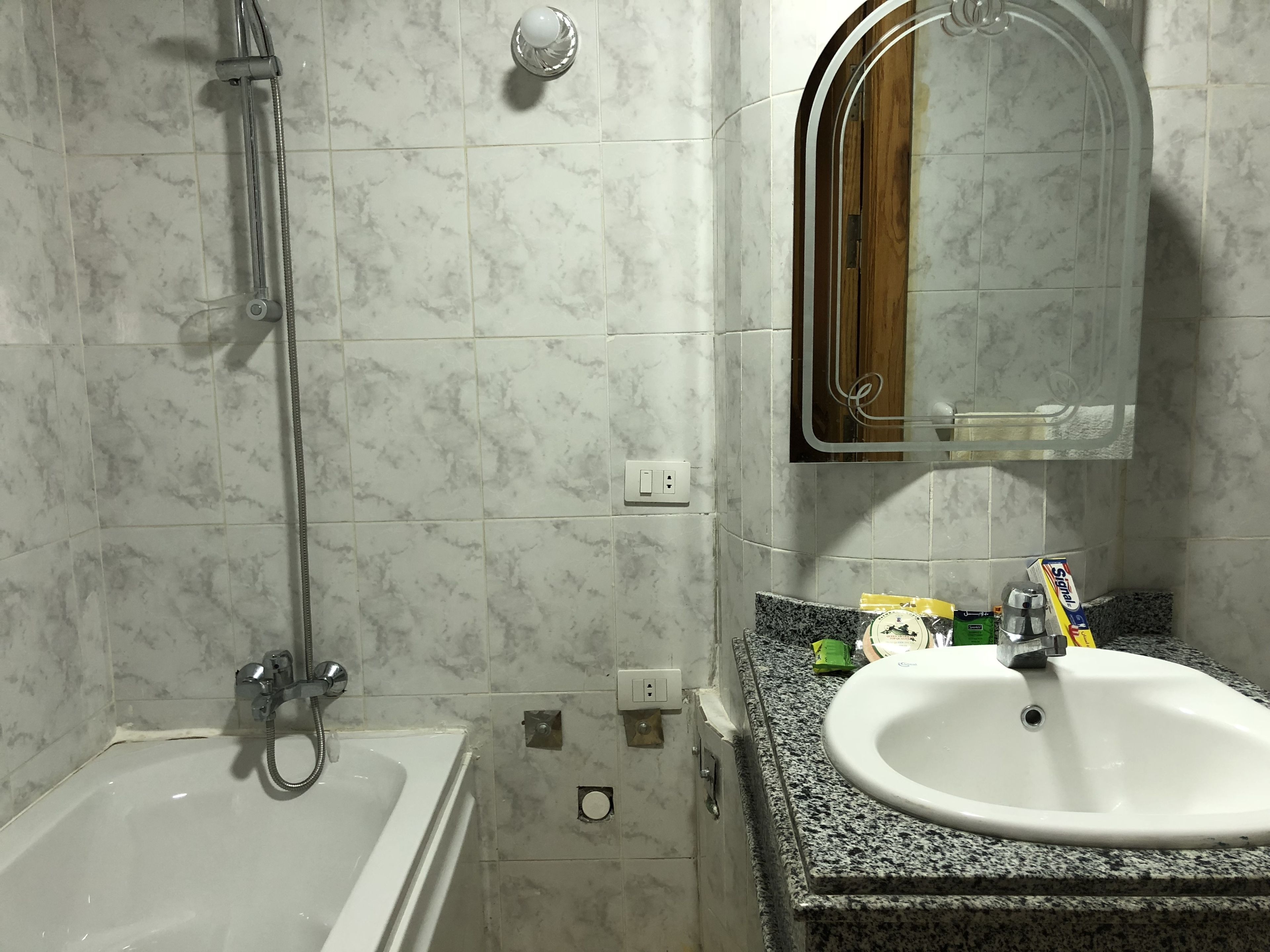 A bathroom with a bathtub, a sink, and a mirror.