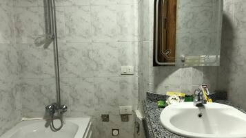 A bathroom with a bathtub, a sink, and a mirror.