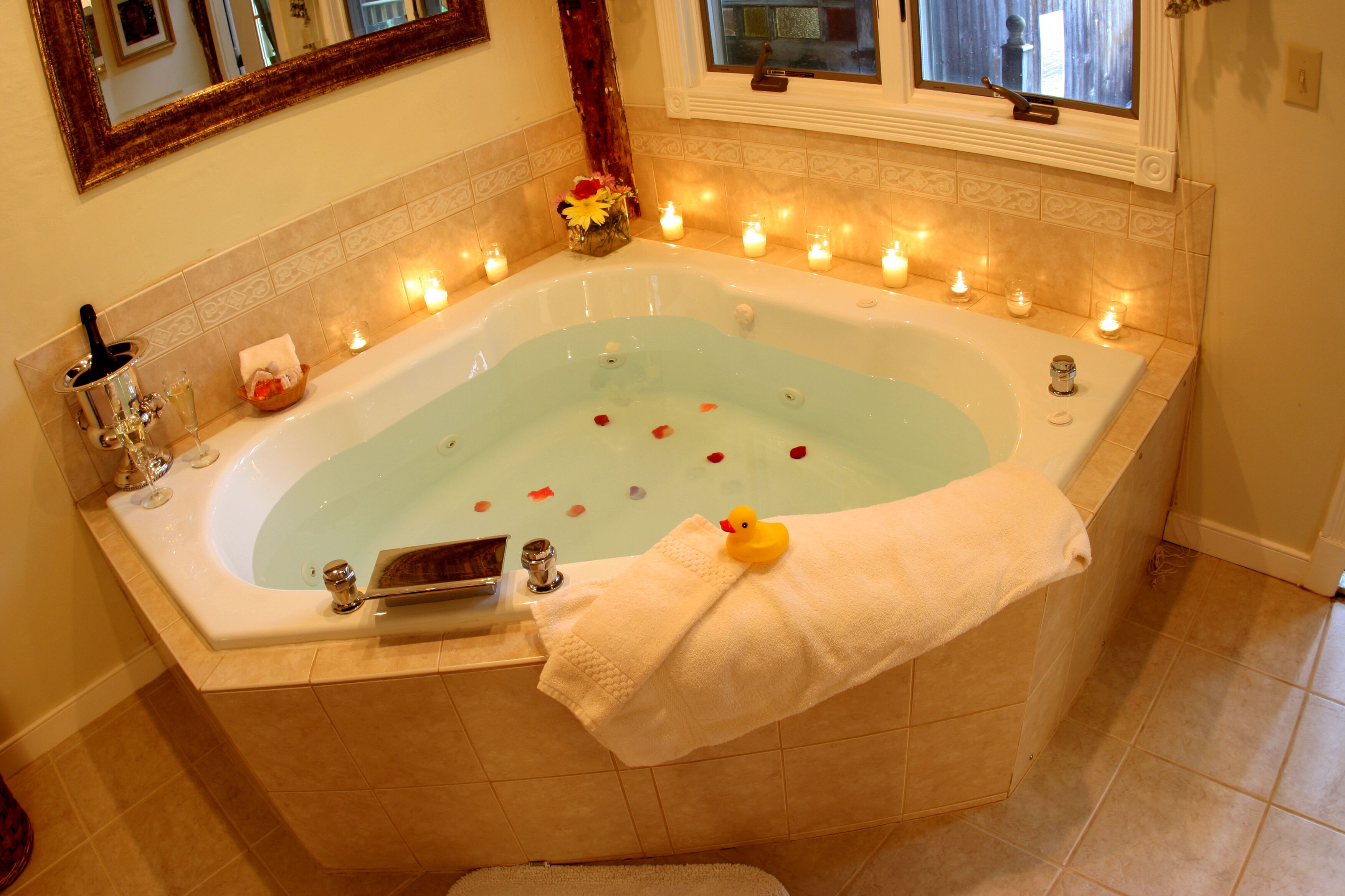 Eine Badewanne mit Kerzen, einem Quietscheentchen und Rosenblättern.