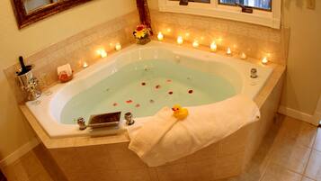 Eine Badewanne mit Kerzen, einem Quietscheentchen und Rosenblättern.