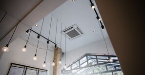 Un plafond orné de luminaires suspendus et muni d’une grille d’aération visible.