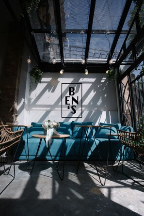 A cozy seating area with a blue sofa, a small table, and a wall-mounted sign that reads "BENS."