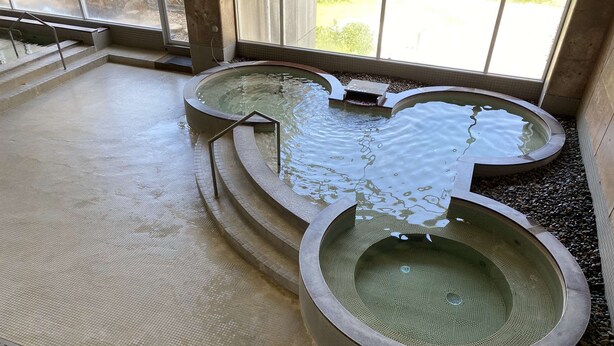 A large indoor pool with multiple sections, surrounded by tiled walls and a window providing natural light. - Panoramaland Kijimadaira (Kijimadaira)