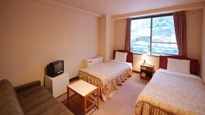 A hotel room with two beds, a small table, a TV, and a window with curtains. - Panoramaland Kijimadaira (Kijimadaira)